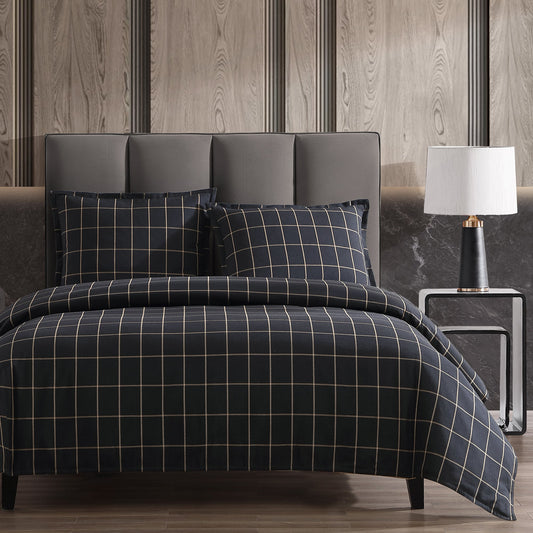Bed with plaid bedding in a bedroom setting with a lamp and headboard.