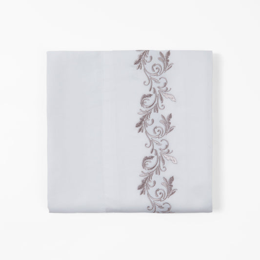 White pillowcase with decorative brown embroidery on a white background