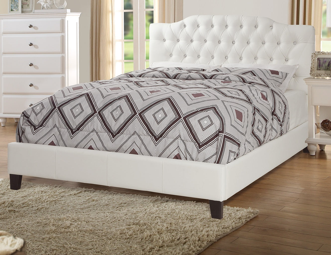 Bedroom with a white upholstered bed and patterned bedding.