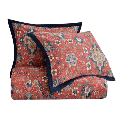 Floral patterned quilt with matching pillow on a white background