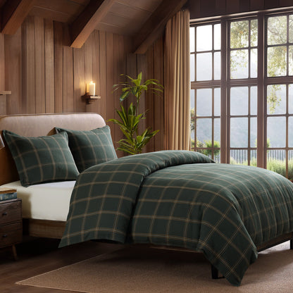 Bedroom with plaid green bedding and large windows.