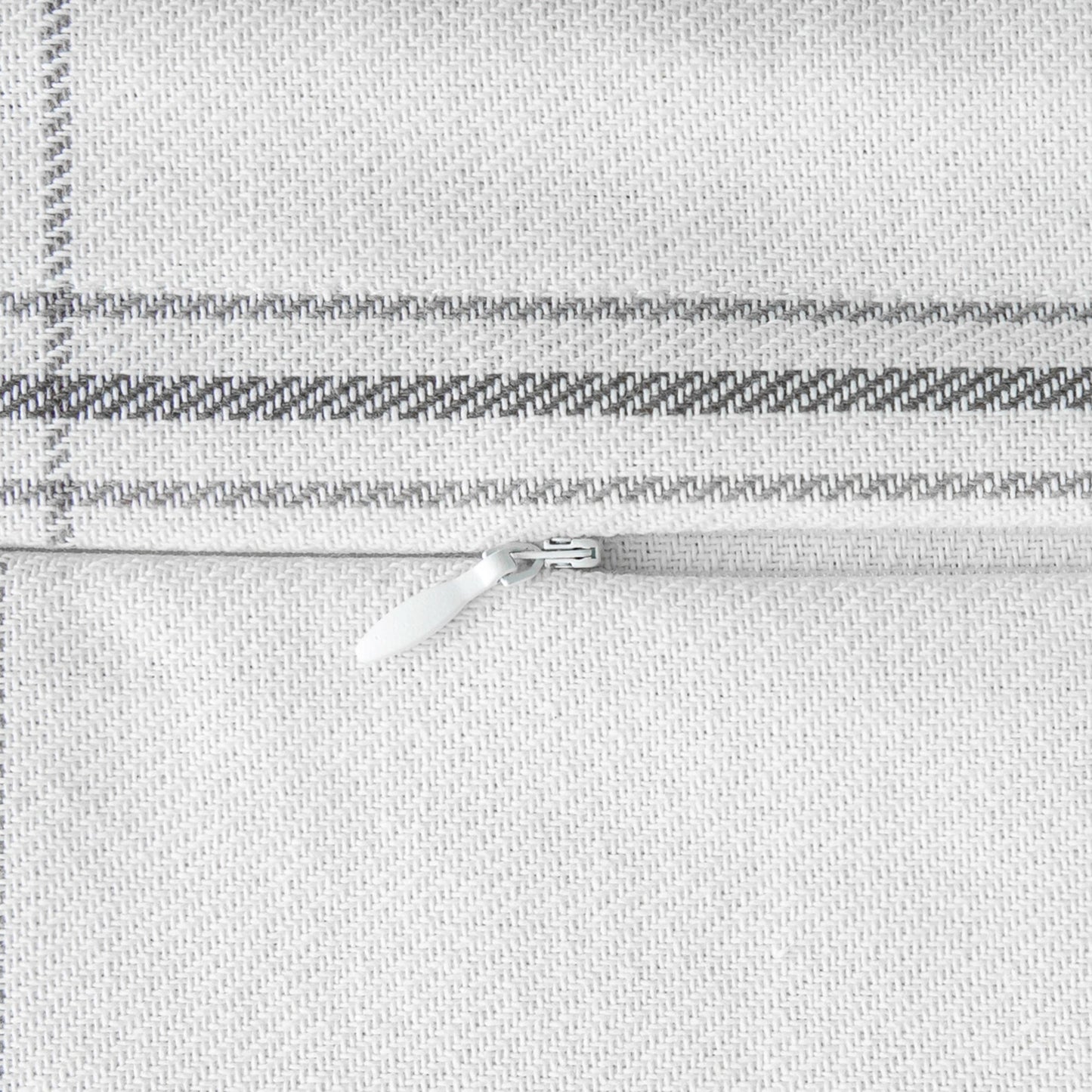 Close-up of a silver zipper on a textured gray fabric background