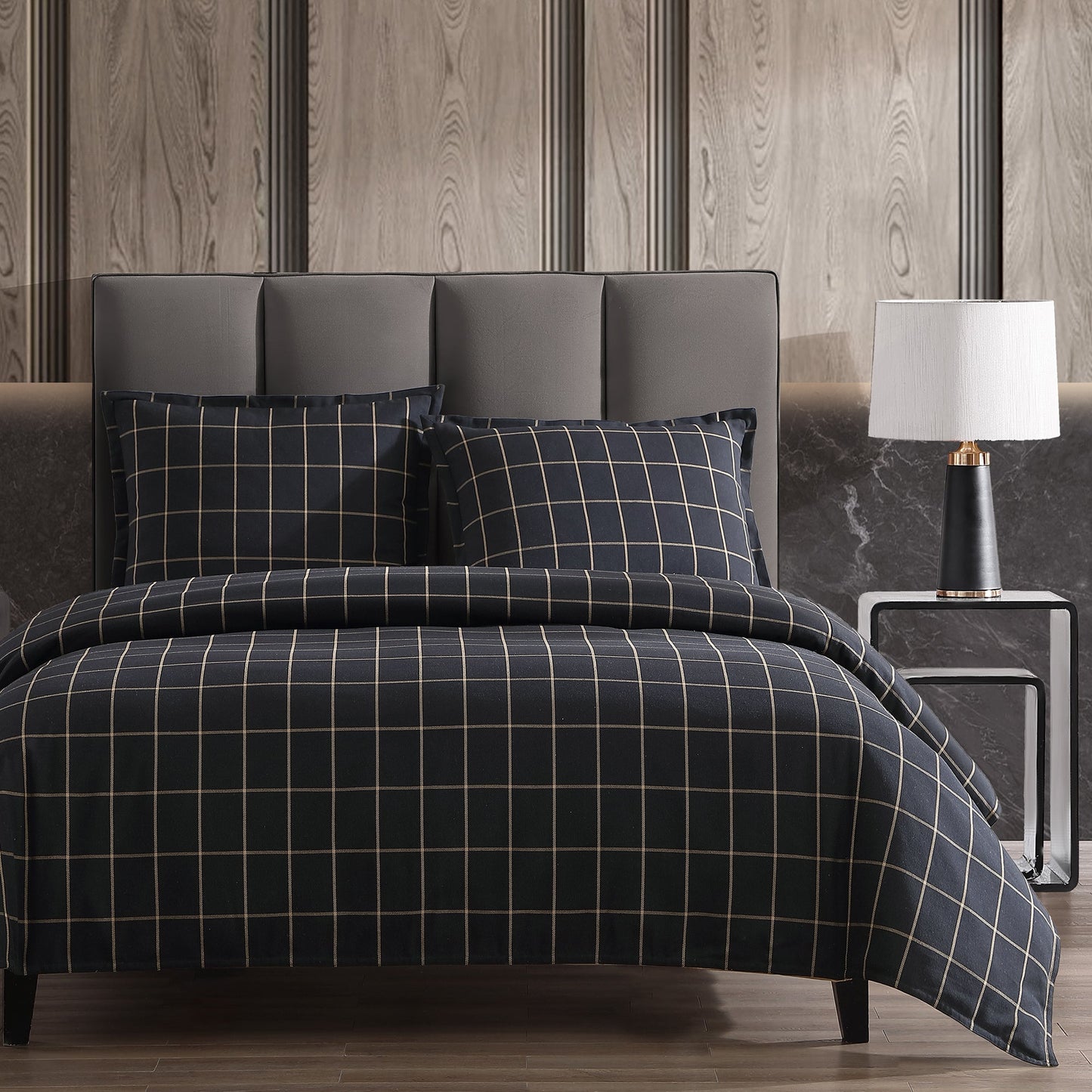 Bed with plaid bedding in a bedroom setting with a lamp and headboard.