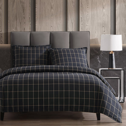 Bed with plaid bedding in a bedroom setting with a lamp and headboard.