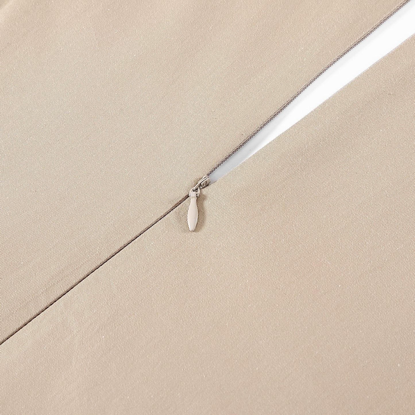 Close-up of a white zipper on beige fabric