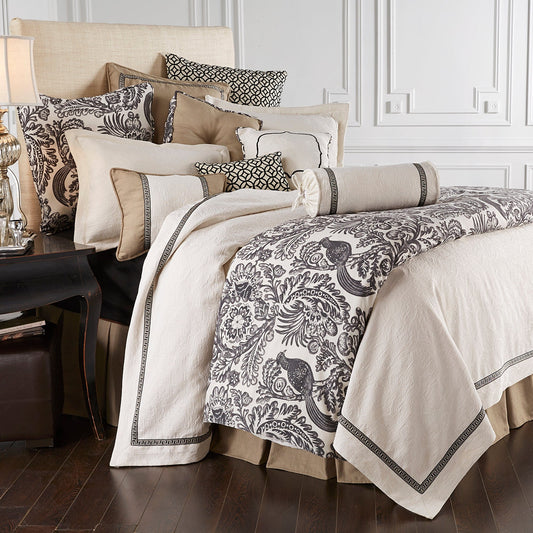 Neatly made bed with patterned bedding and pillows in a bedroom setting.