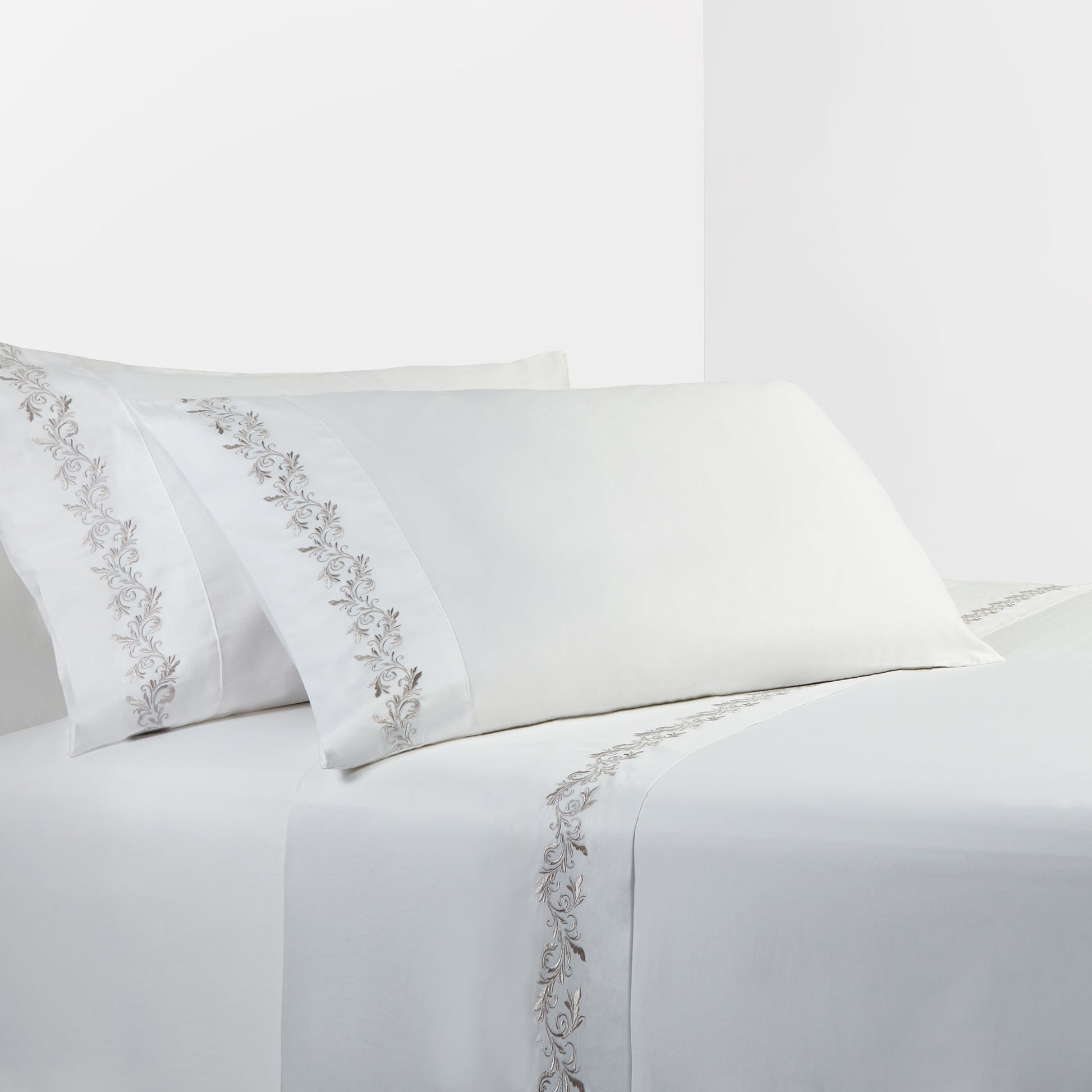 White bed sheets with silver embroidery on a white background