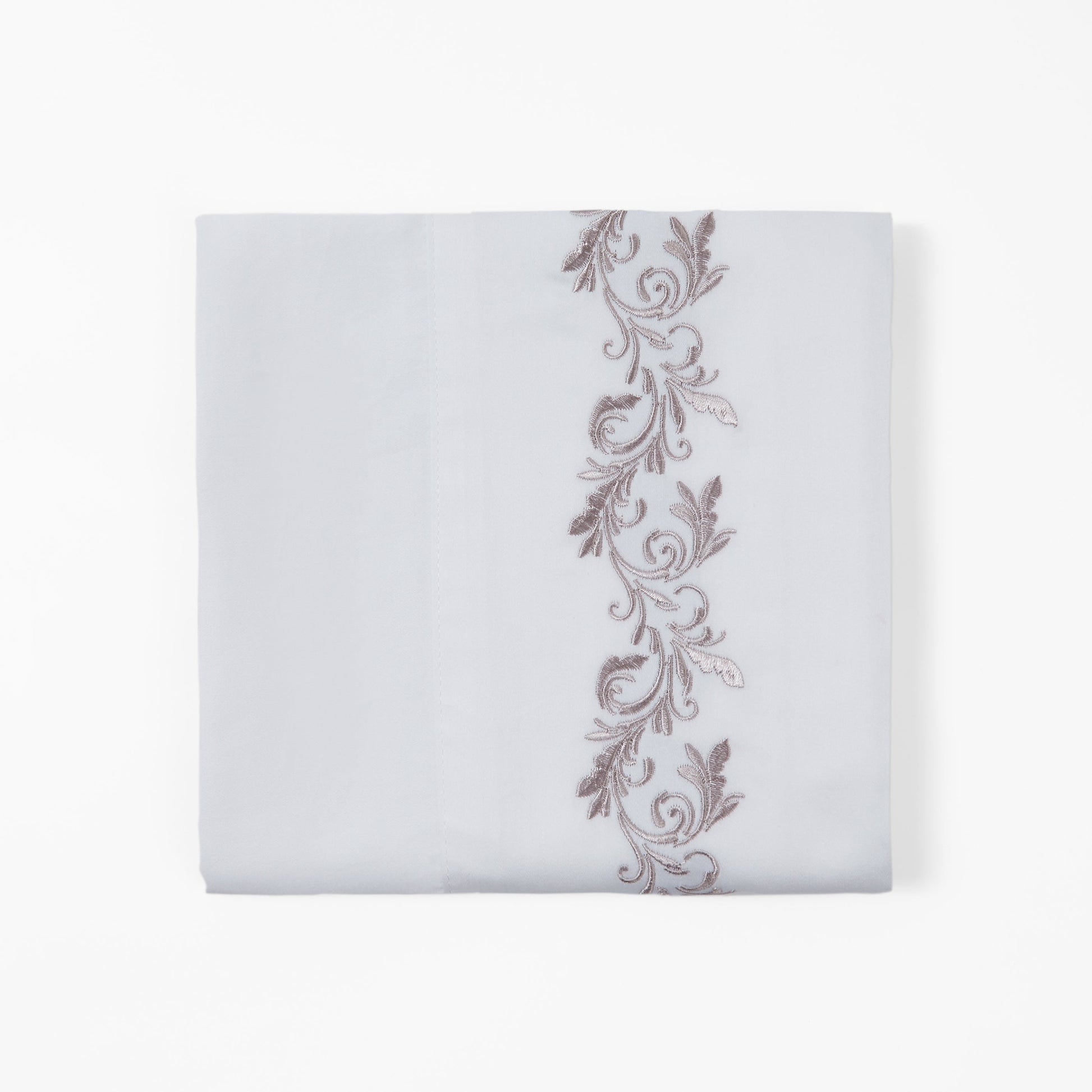 White pillowcase with decorative brown embroidery on a white background