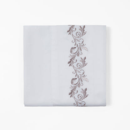 White pillowcase with decorative brown embroidery on a white background