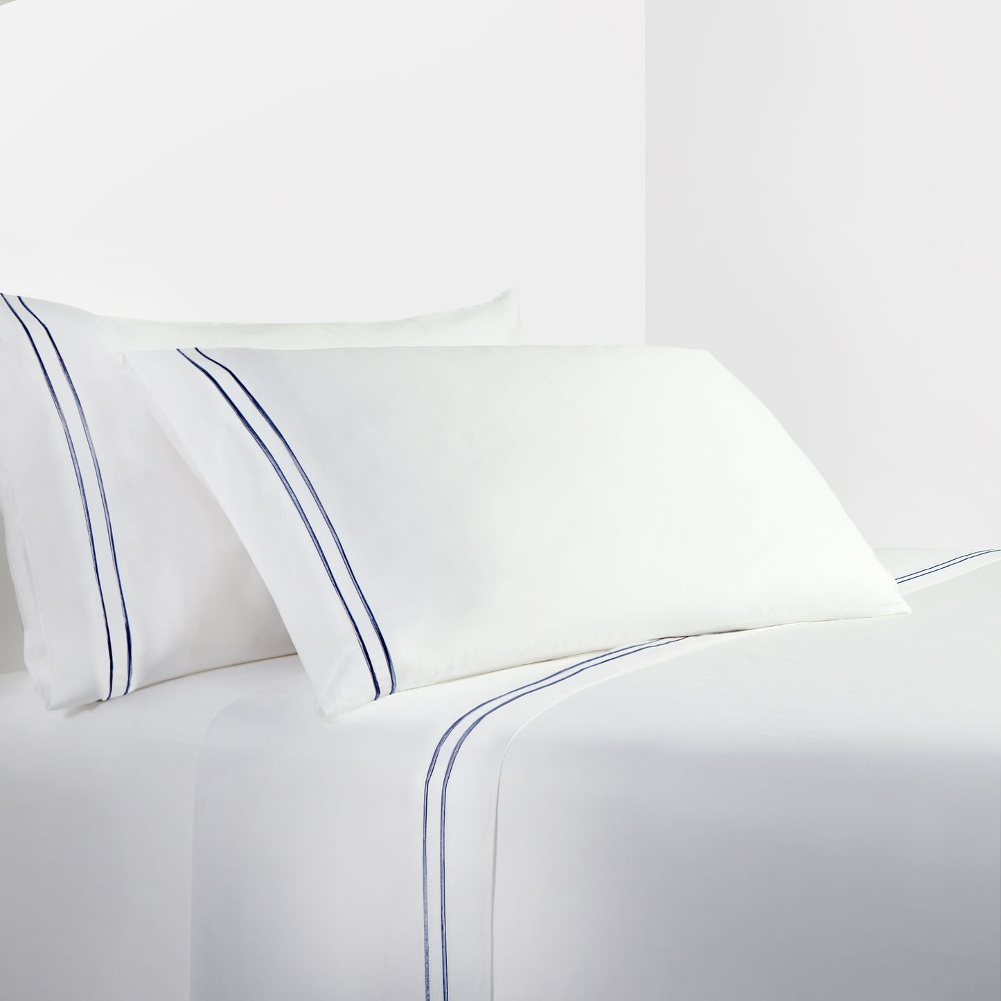 White bed sheets with blue piping on a white background