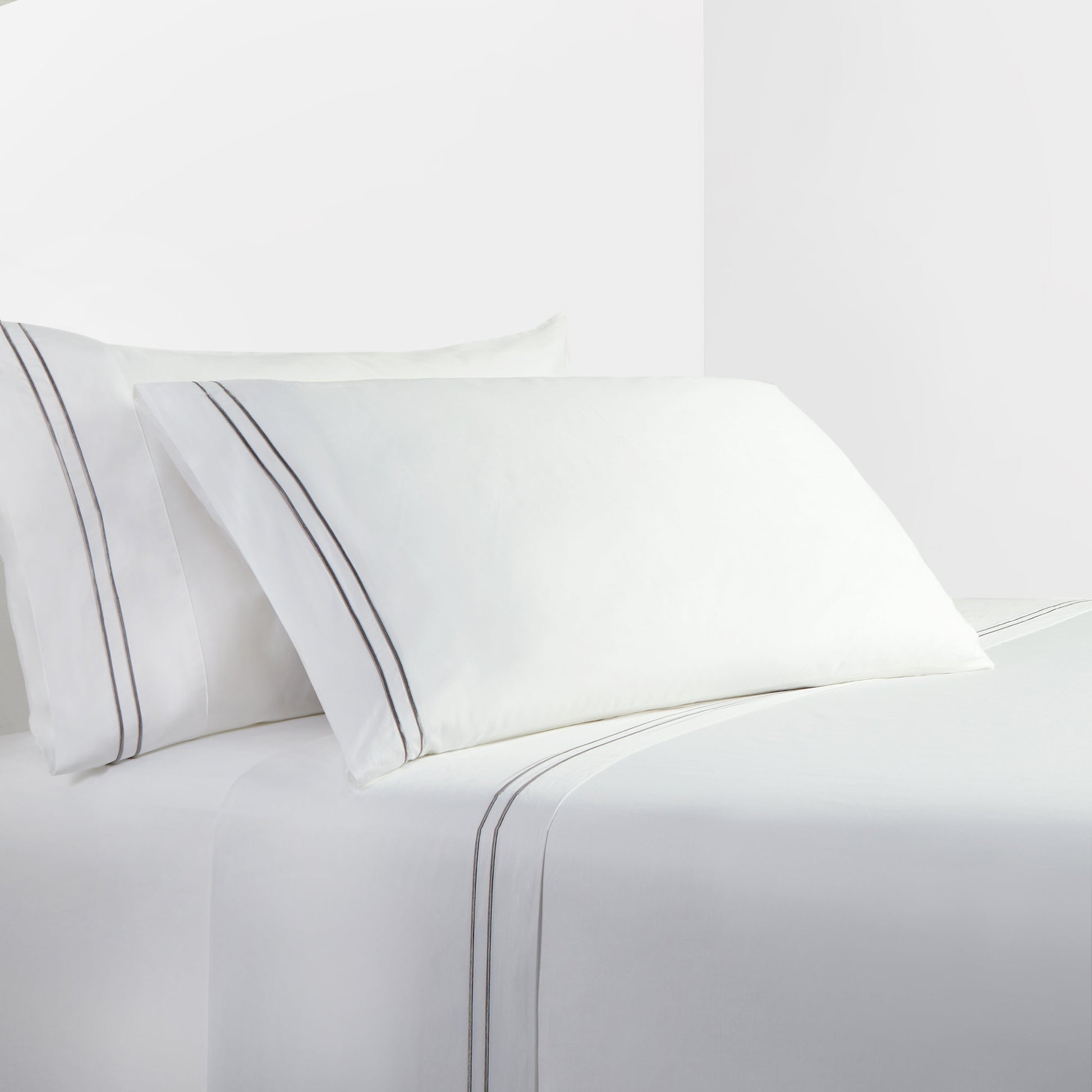 White bed sheets and pillows with a subtle stripe on a white background