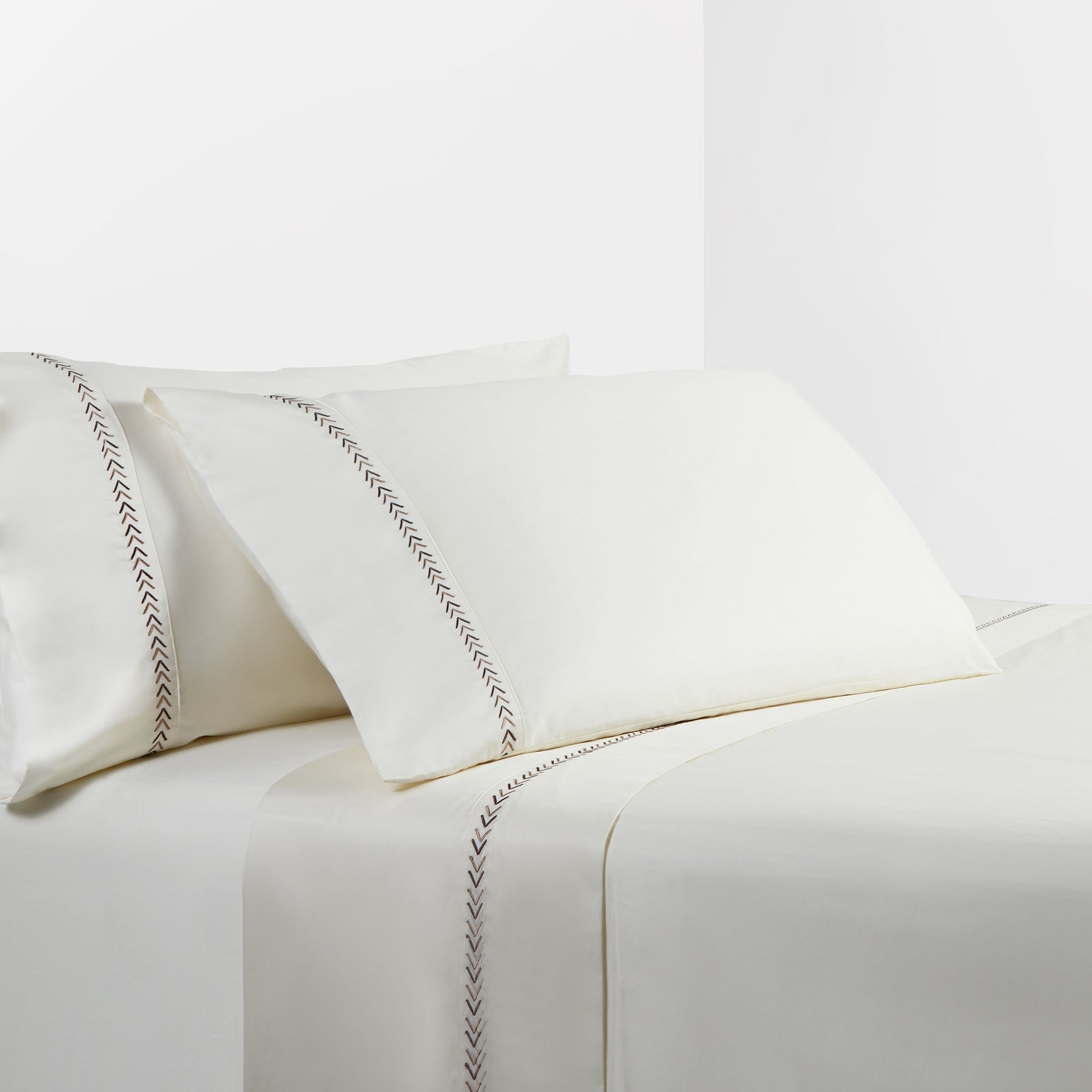 White bed sheets with decorative stitching on a white background