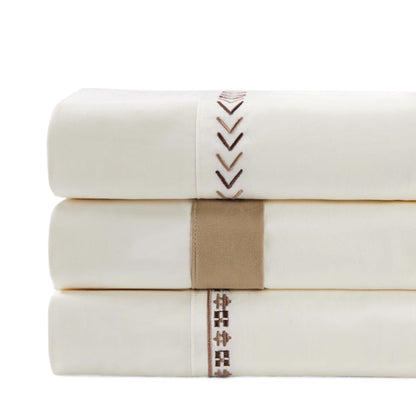 Stack of white towels with brown decorative stitching on a white background