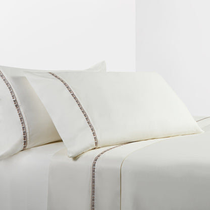 White bed sheets with decorative trim on a white background