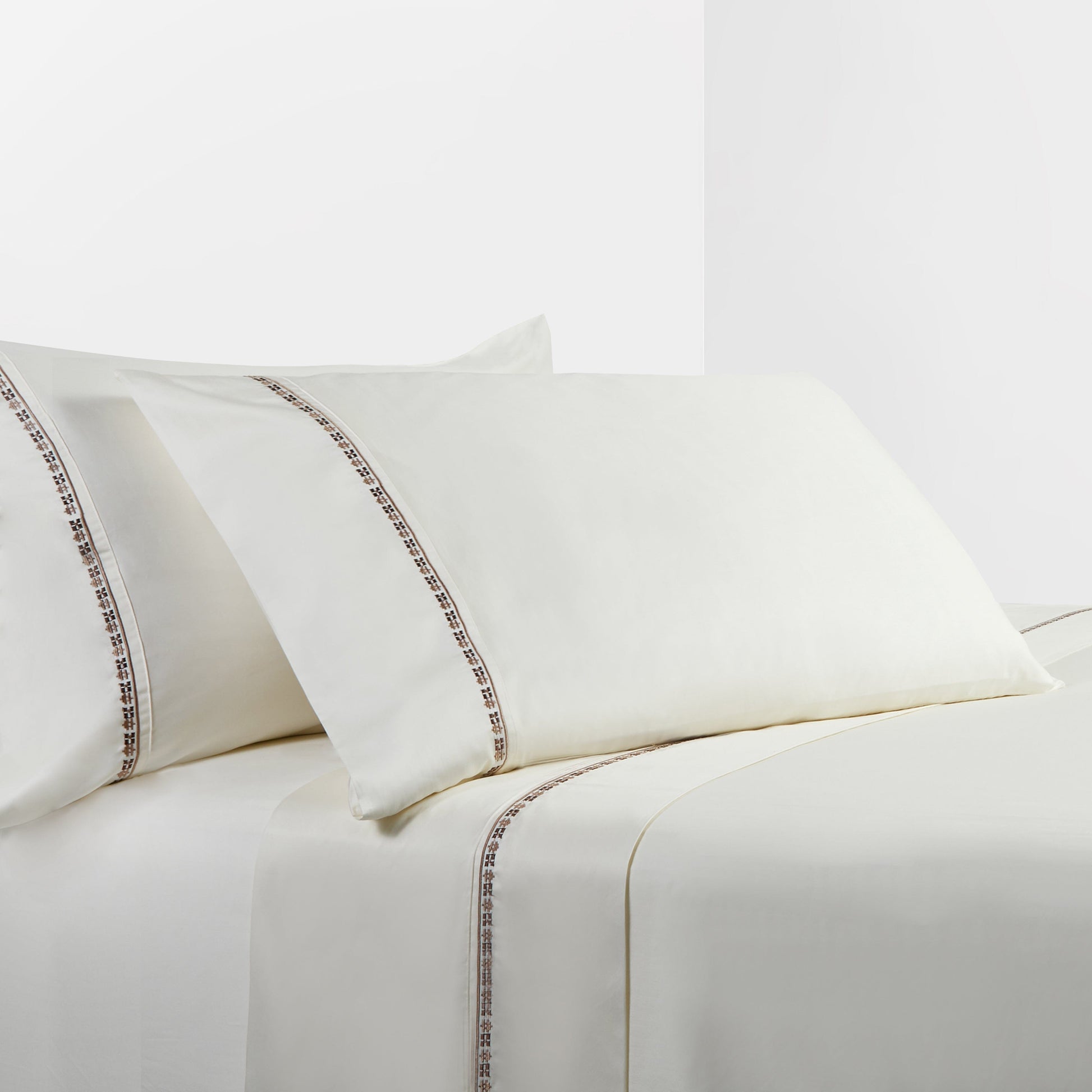 White bed sheets with decorative trim on a white background
