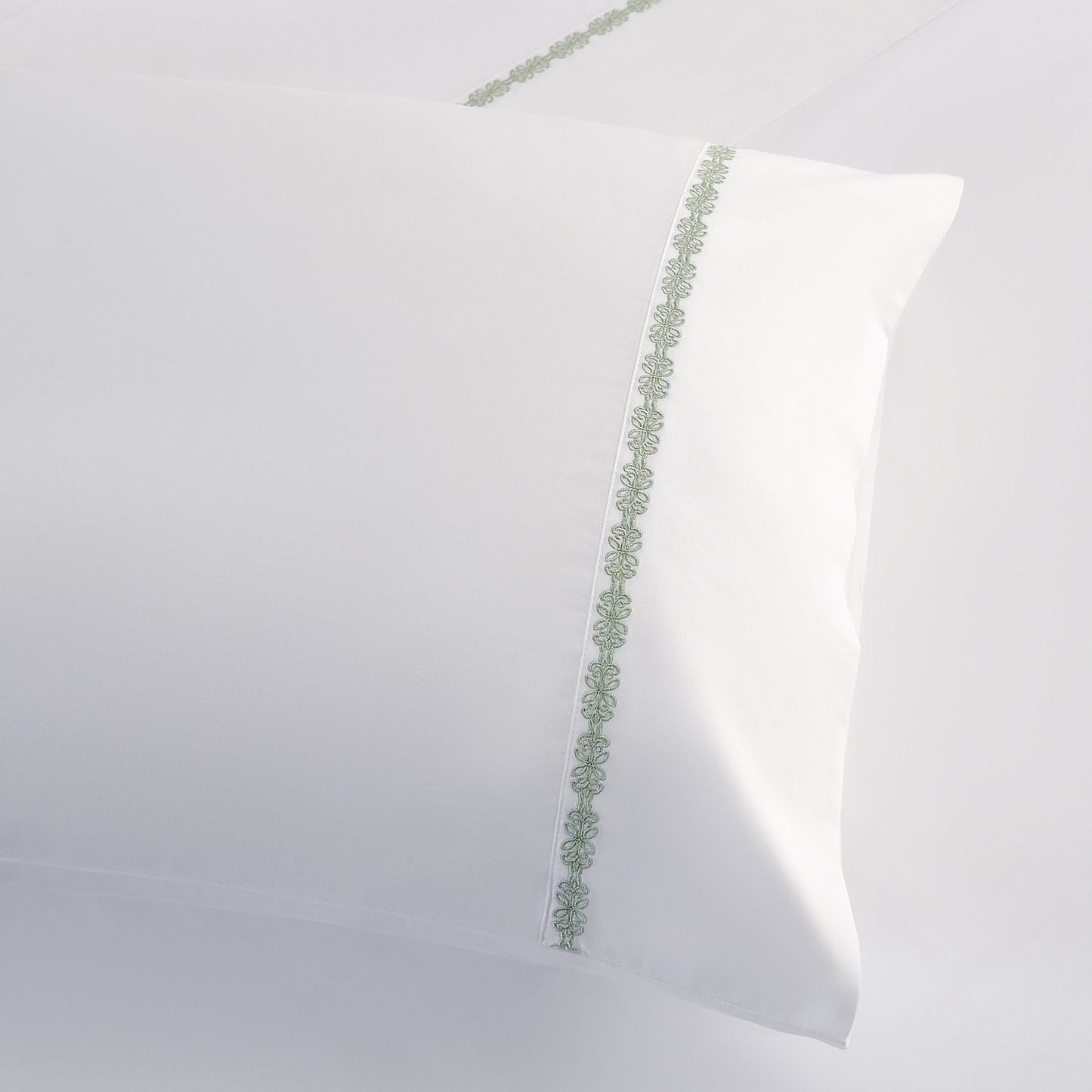 White pillow with green decorative trim on a white background