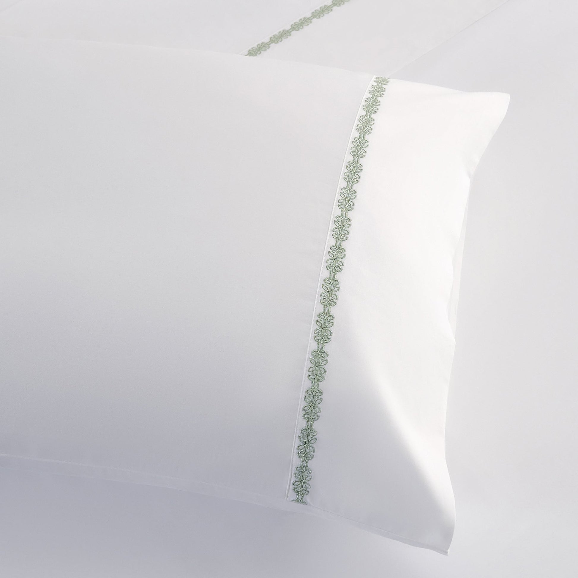 White pillow with green decorative trim on a white background