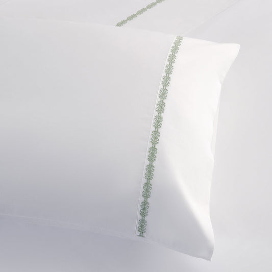 White pillow with green decorative trim on a white background