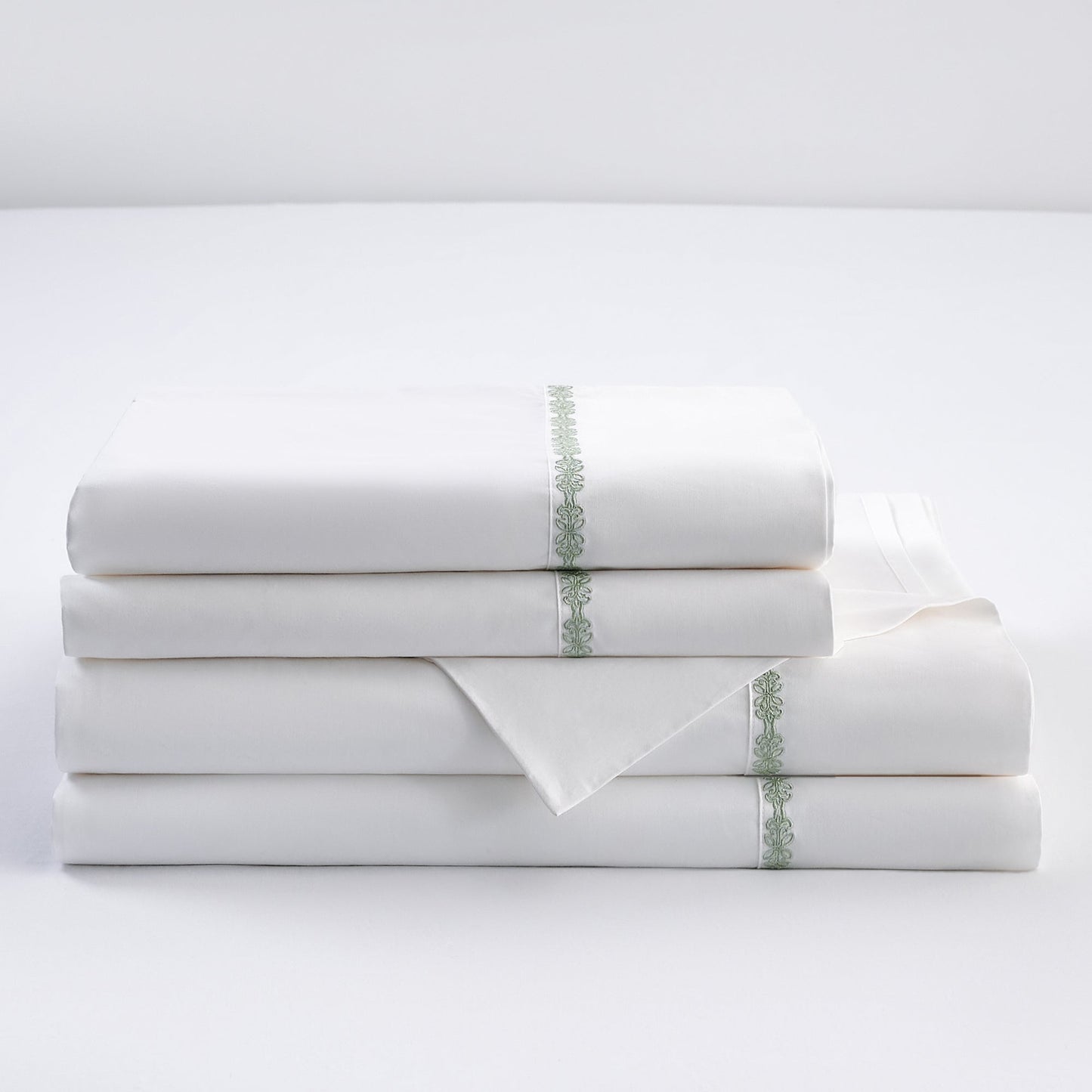Stack of white folded towels with decorative green stripes on a light gray background