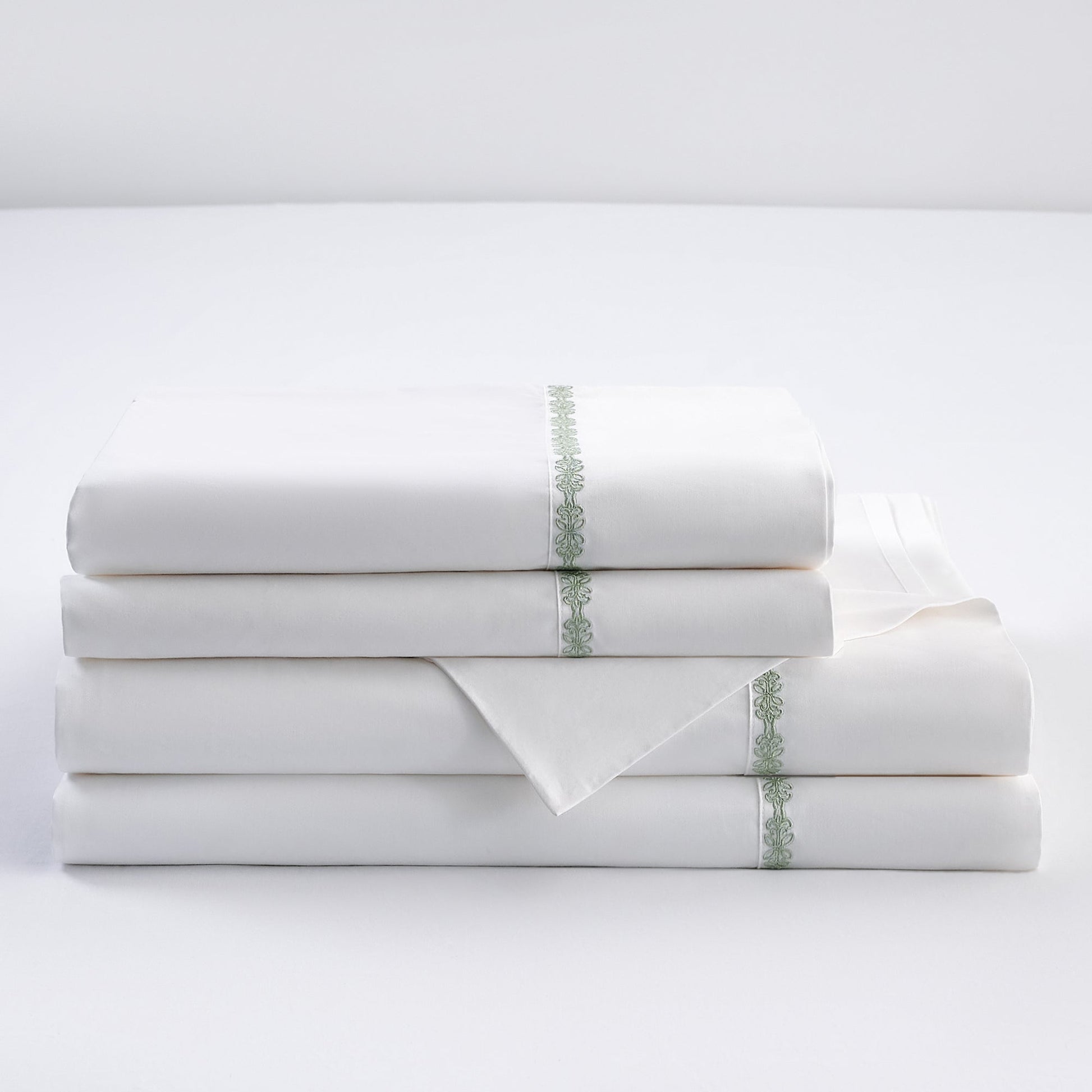 Stack of white folded towels with decorative green stripes on a light gray background