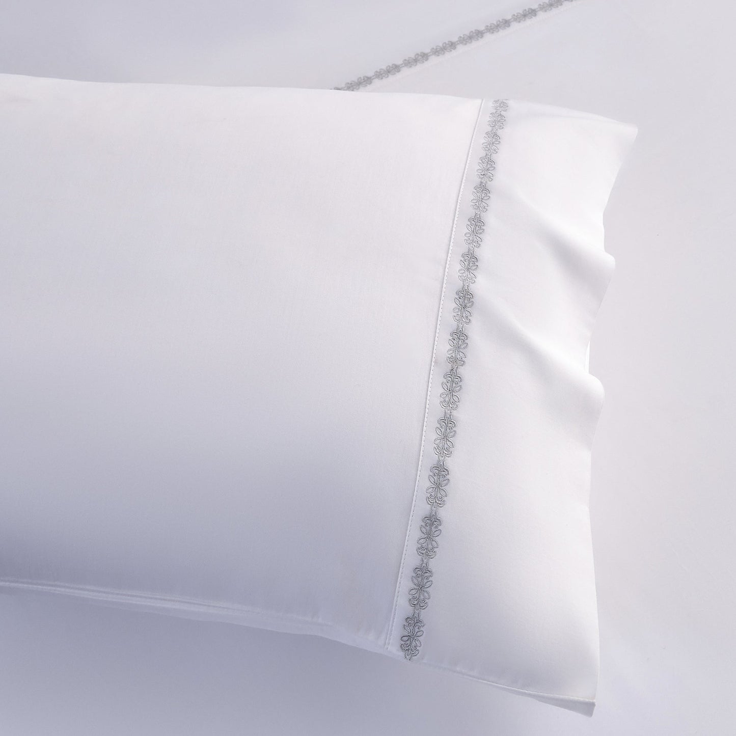 White pillowcase with decorative trim on a light gray background
