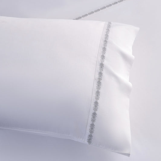 White pillowcase with decorative trim on a light gray background