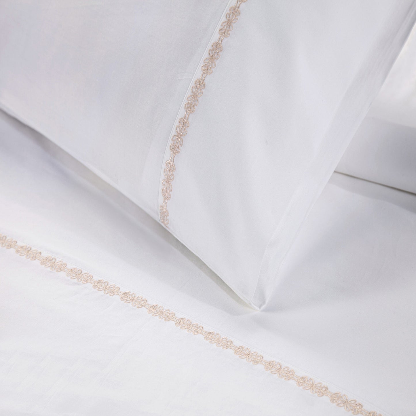 White pillows with decorative gold trim on a white background