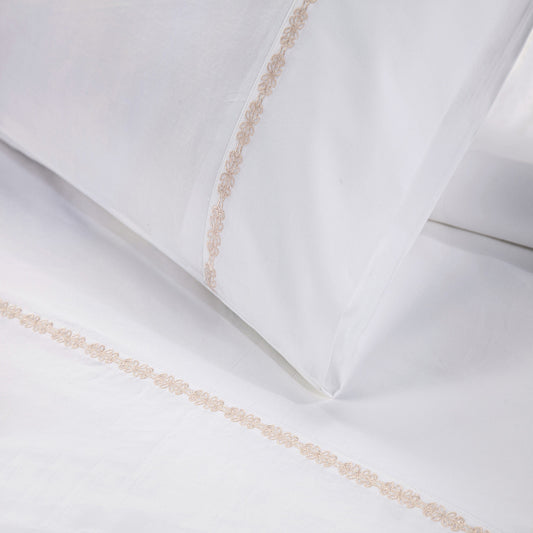 White pillows with decorative gold trim on a white background