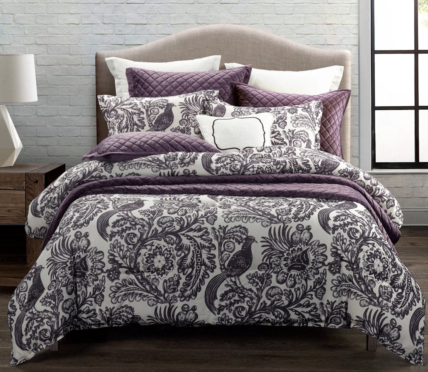 Bed with purple and white patterned bedding in a room setting.