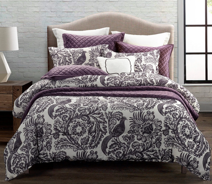 Bed with purple and white patterned bedding in a room setting.
