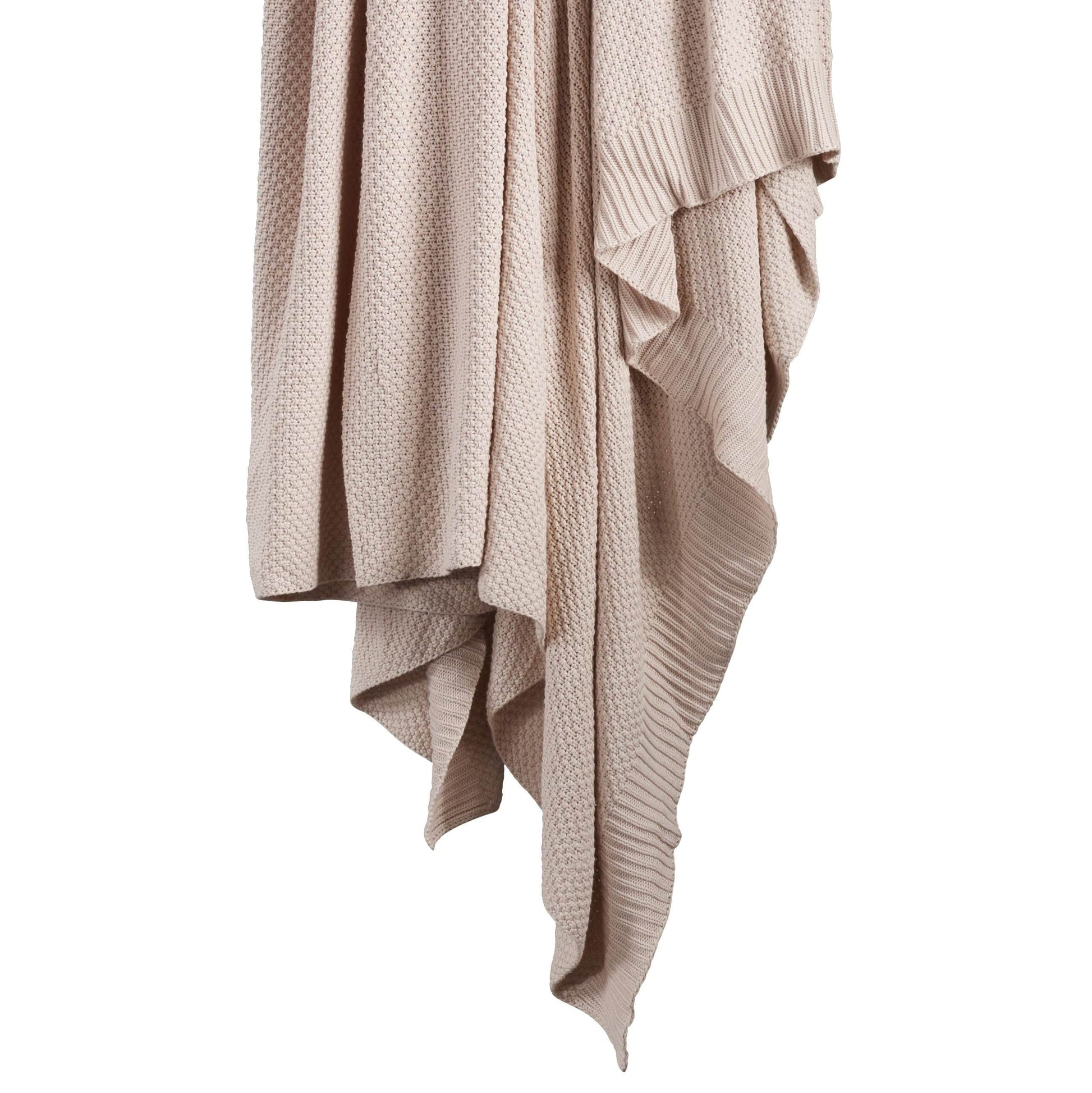Beige knitted blanket draped over a white background