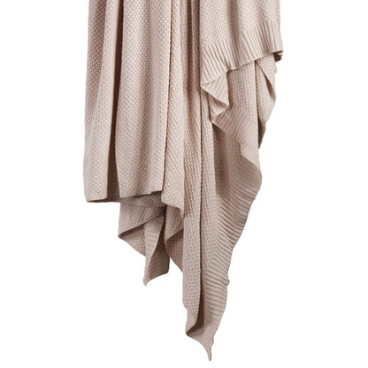 Beige knitted blanket draped over a white background
