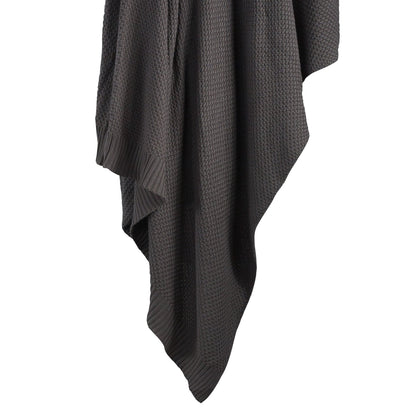 Dark gray textured blanket draped over a white background