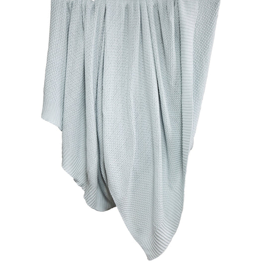 Light blue knitted blanket draped over a white surface